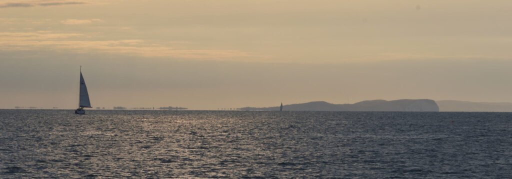 The Solent before sunrise, a yacht under sail off the Isle of Wight